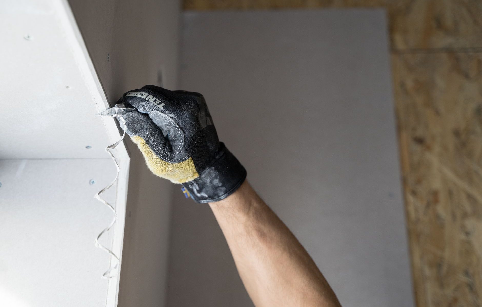 Handwerker hält eine Trockenbauplatte an der Wand