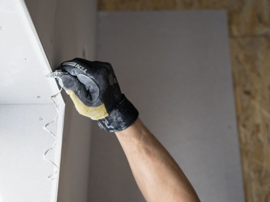 Handwerker hält eine Trockenbauplatte an der Wand